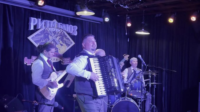 Клубное выступление. Аккордеонист играет соло в сопровождении группы музыкантов